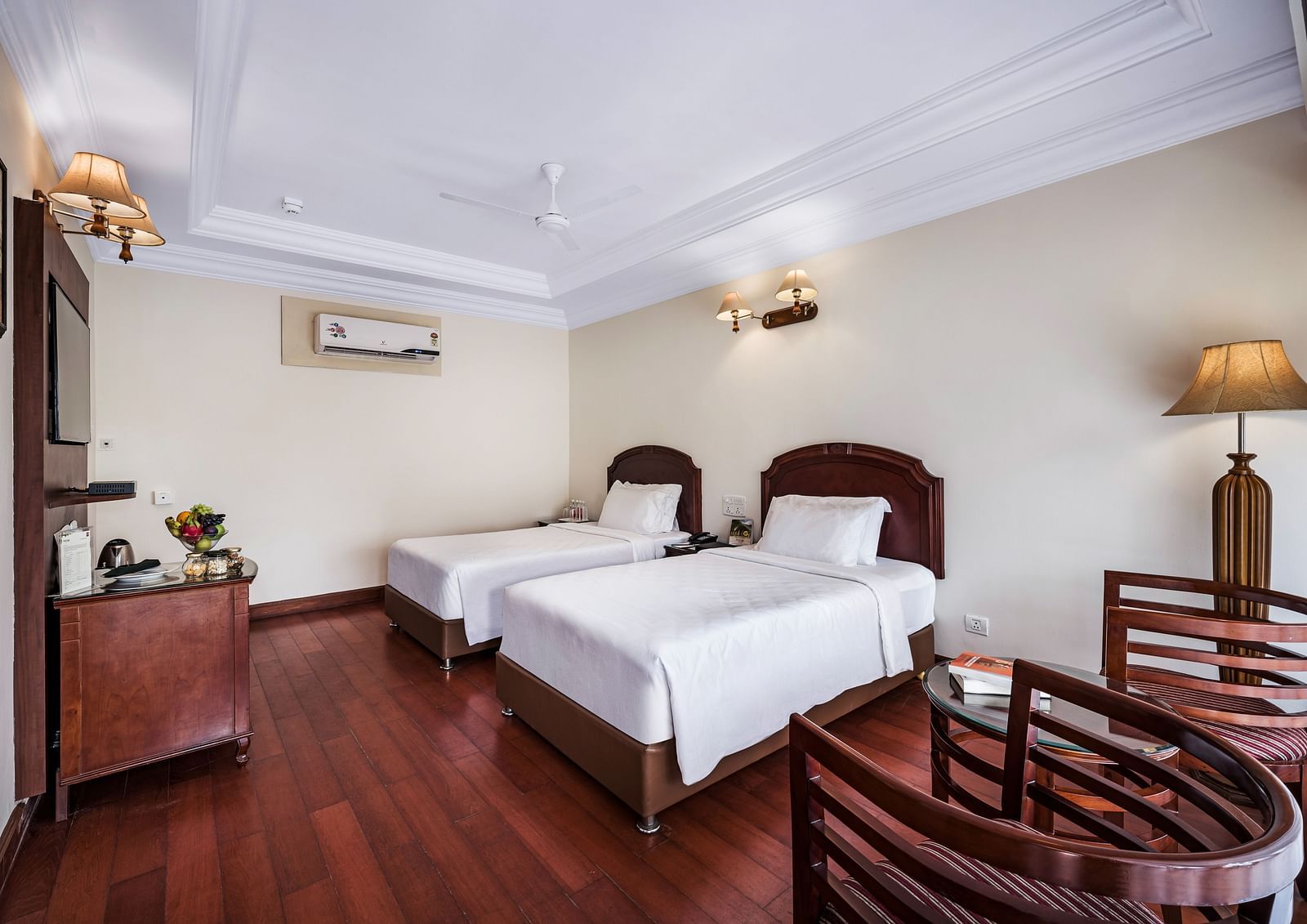 An image of the River View Room With Verandah featuring two single beds, bed side table, lamps, flat screen TV, and chairs - GReaT Trails River View Resort Thanjavur By GRT Hotels