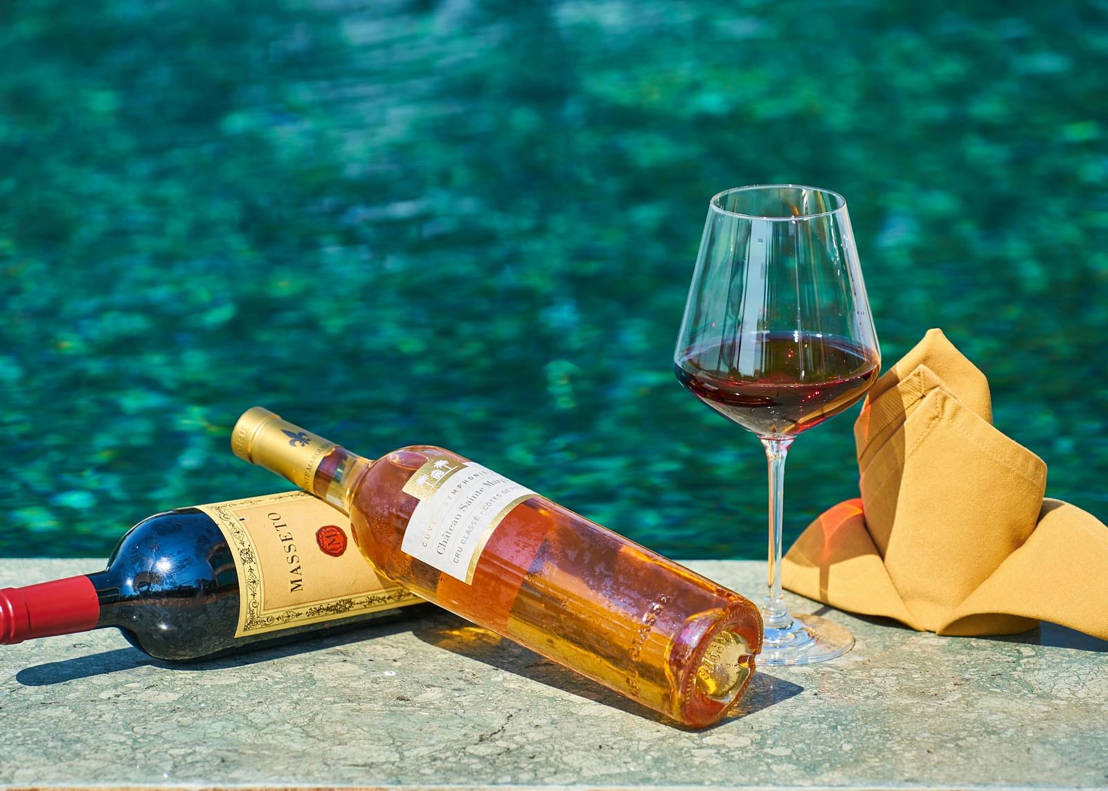 Two bottles of wine placed by a pool, with crystal-clear water in the background - Hotel 39, Jamaica