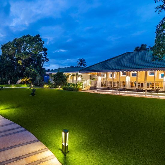 A sunset view of the Bonita Lawns with lighting along the pathway and floor lamps beside it