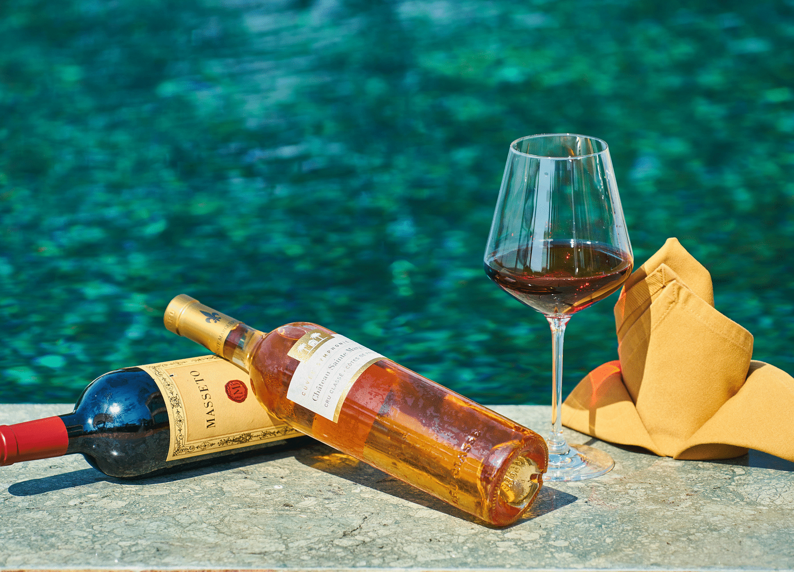 Two bottles of wine placed by a pool, with crystal-clear water in the background - Hotel 39, Jamaica