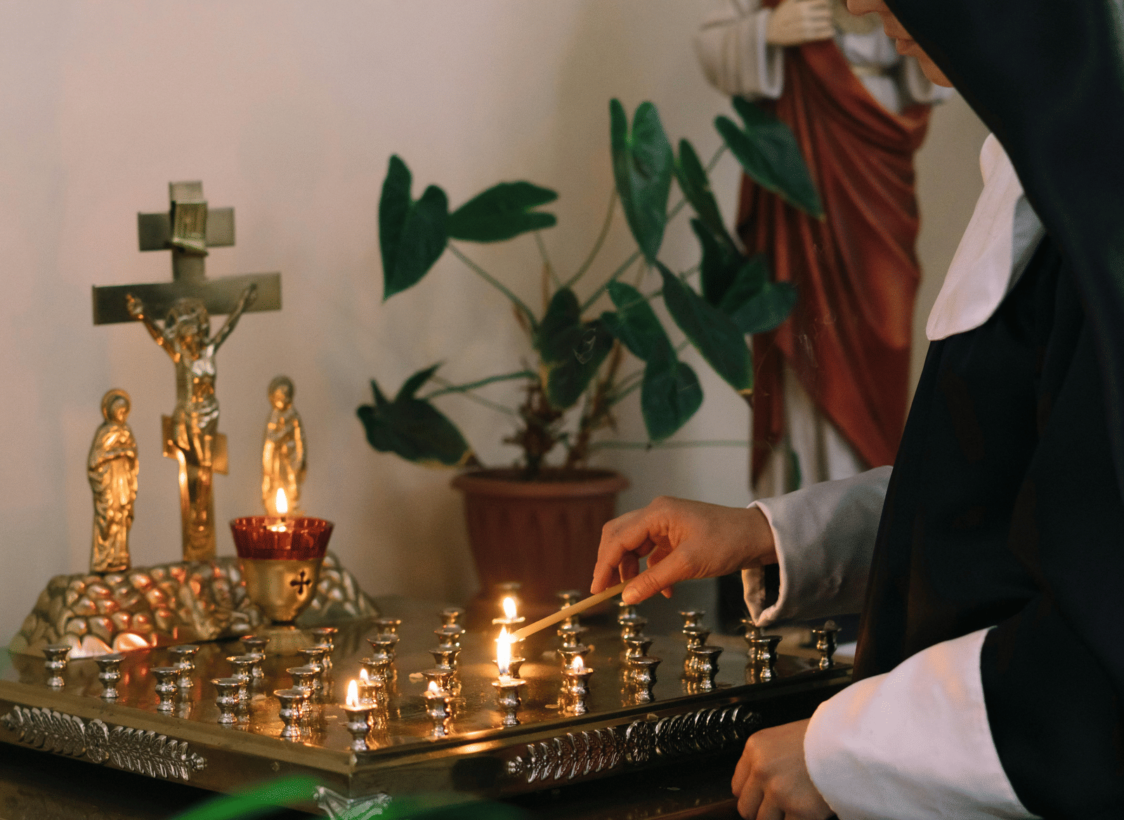 A nun lighting candles at a church.
