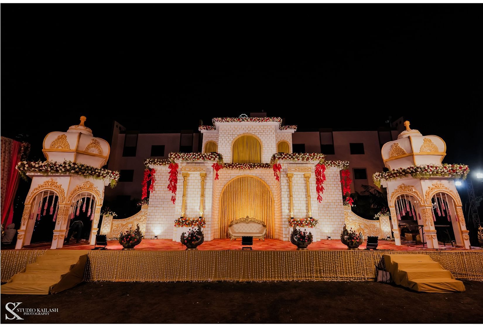 A podium adorned with castle-like structures stands against a backdrop, creating a regal setting for what appears to be a wedding. - Wedlock Greens Hotel Resorts Dhanbad