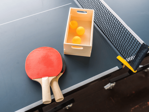 two table tennis rackets and balls laying on the tennis table