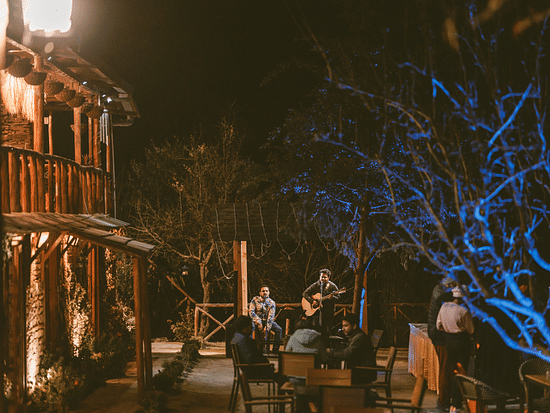  A lively outdoor gathering with people seated around a musician playing a guitar - The Manor Luxury Hotel, Shimla