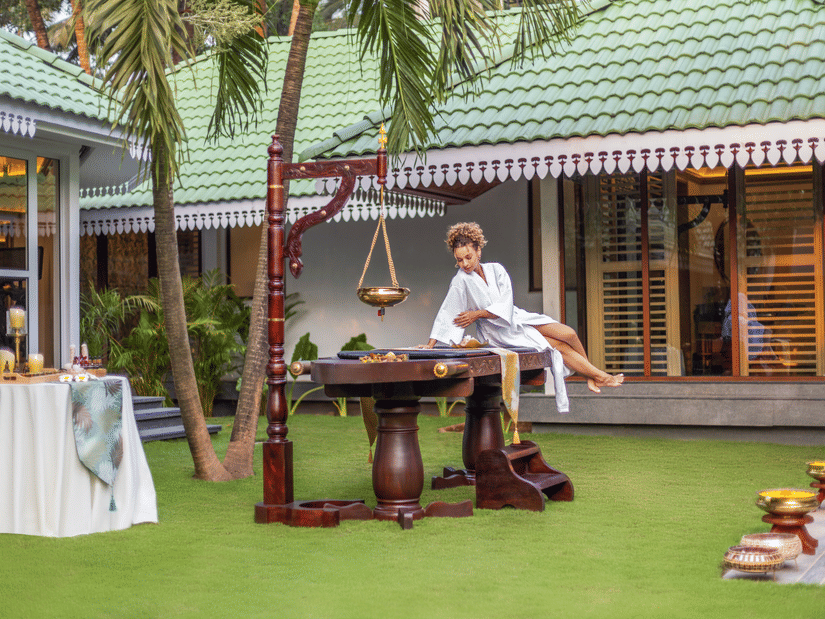 Guest enjoying a traditional spa treatment in an open-air garden setting at the resort | Heritage Village Resorts & Spa, Goa