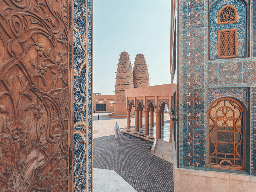 A view of Katara village in Doha with beautiful mosaic walls on the buildings and a person walking.