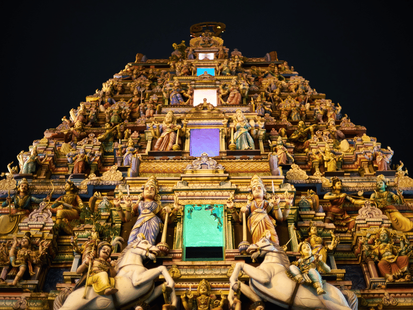 an old south indian style temple with lots of horses and other idols constructed on the exterior