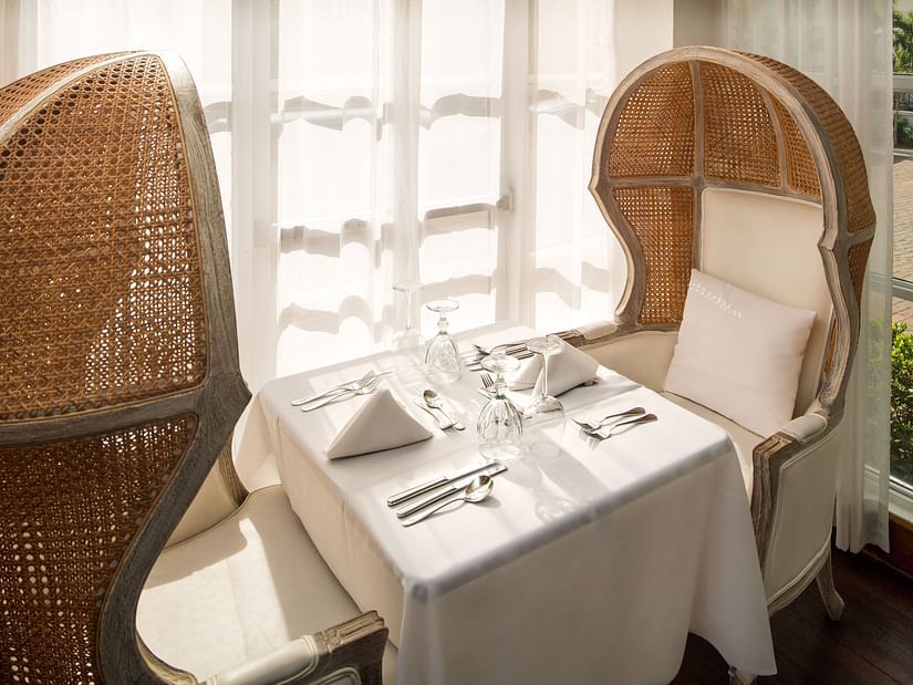 A cosy corner at our Kingston Restaurant with cushioned chairs and a table with cutlery - S Hotel Kingston, Jamaica