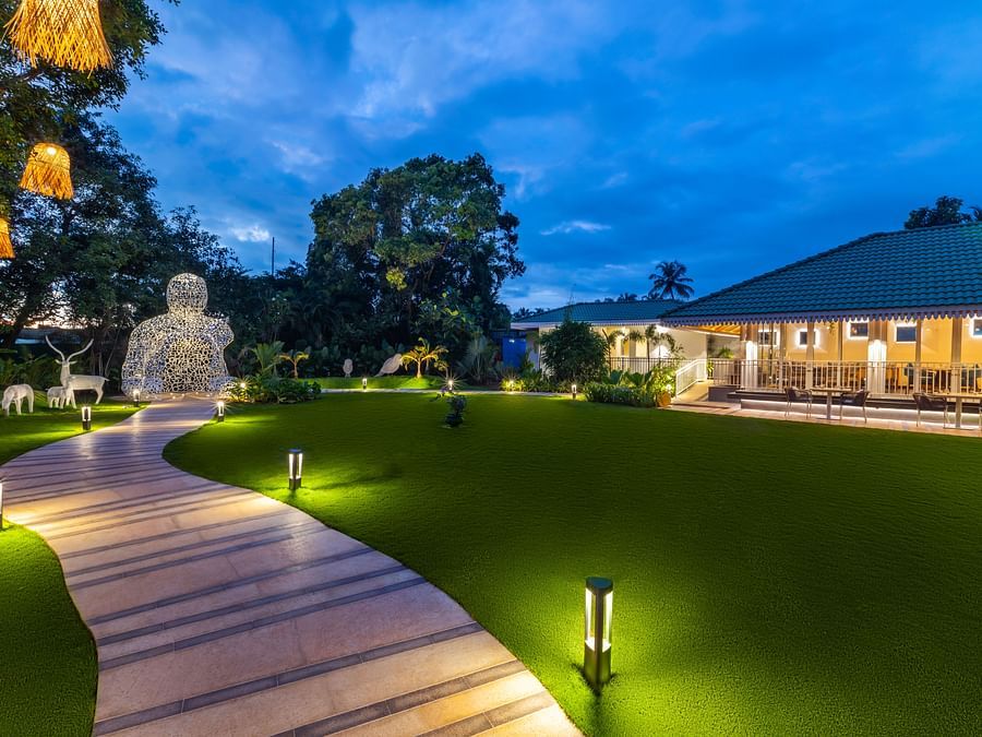 A sunset view of the Bonita Lawns with lighting along the pathway and floor lamps beside it