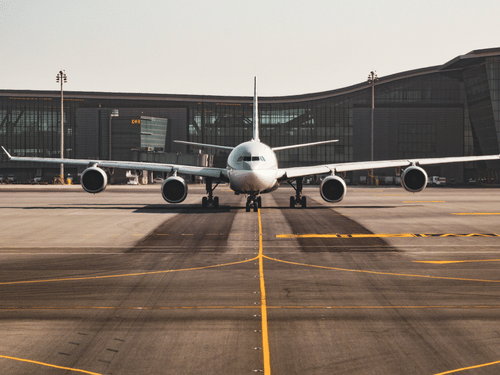 An airplane parked on a deserted runway with a building in the background. 