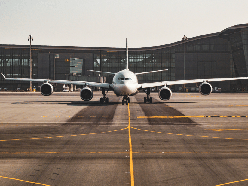 Airplane parked on a desserted runway with a building in the background. 