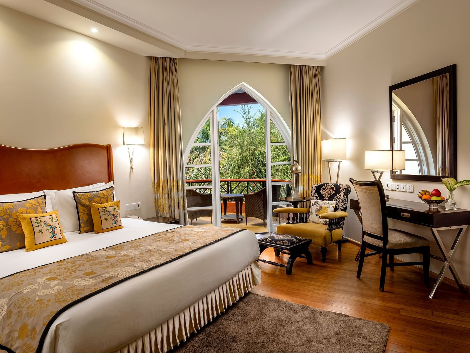 a double bed with side tables, lamps and mirror on the wall inside Deluxe Suite - Caravela Beach Resort Goa