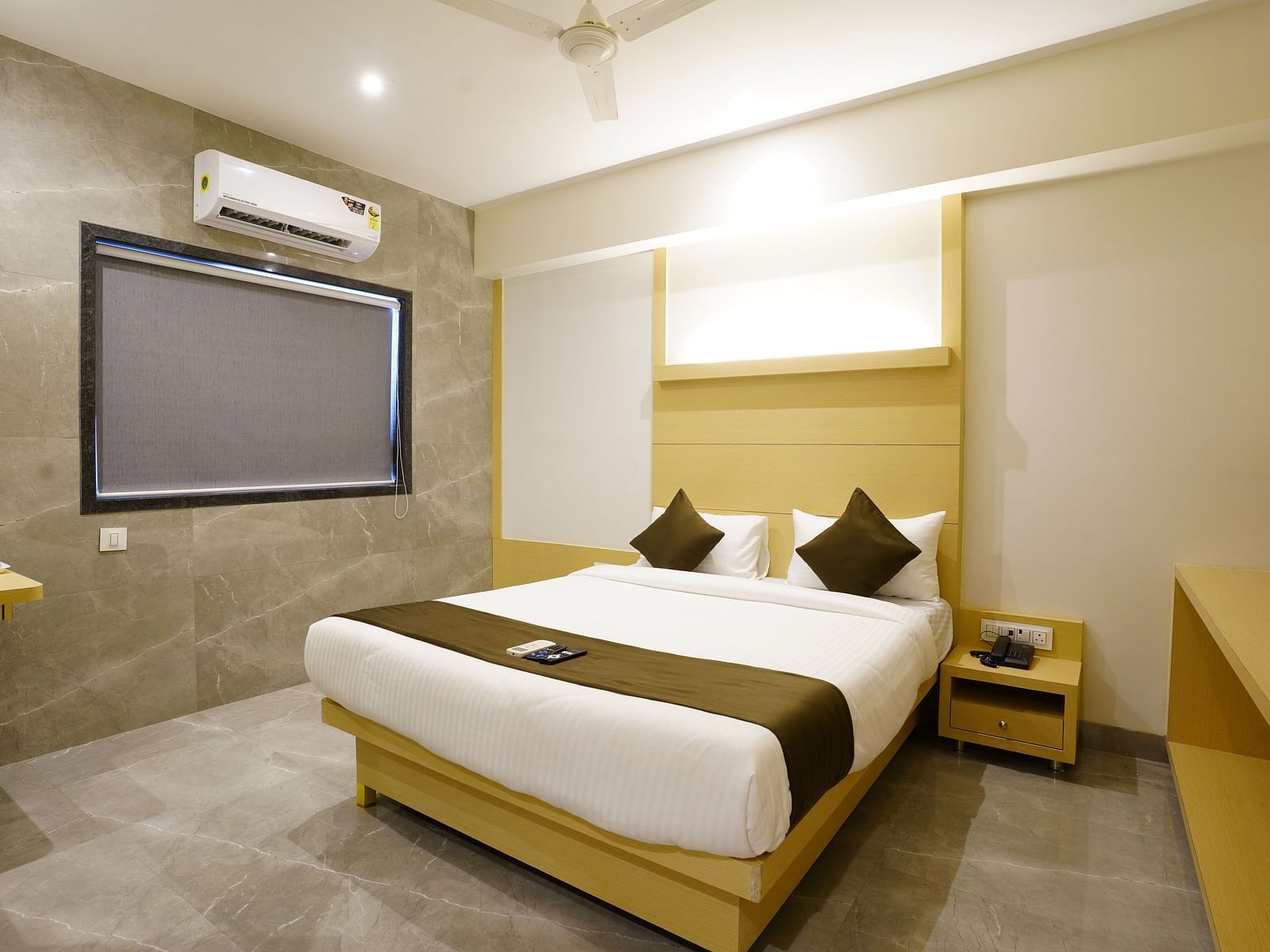 Hotel room with a double bed, white linens, brown runner, two brown pillows, and a wall-mounted television and AC - Shyanu Lords Eco Inn Airoli