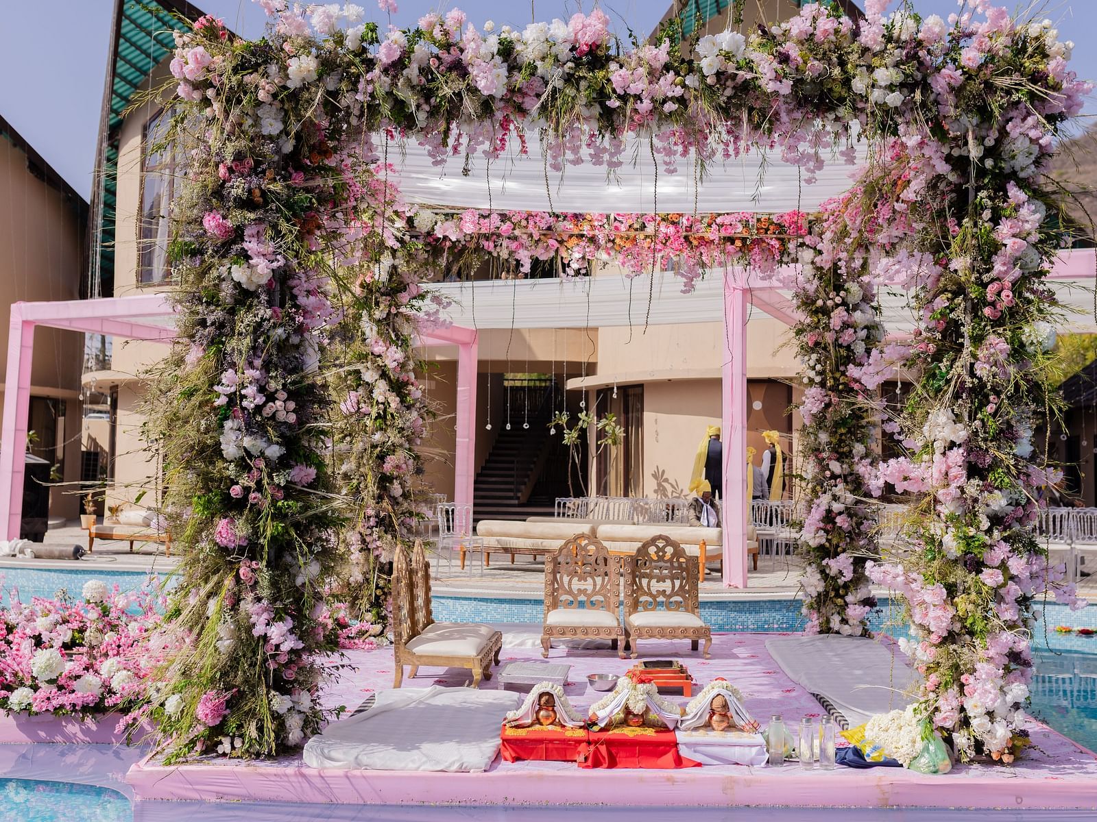 A wedding ceremony setup features a floral archway by a pool | The Qualia Resort Club & Brewery, Udaipur