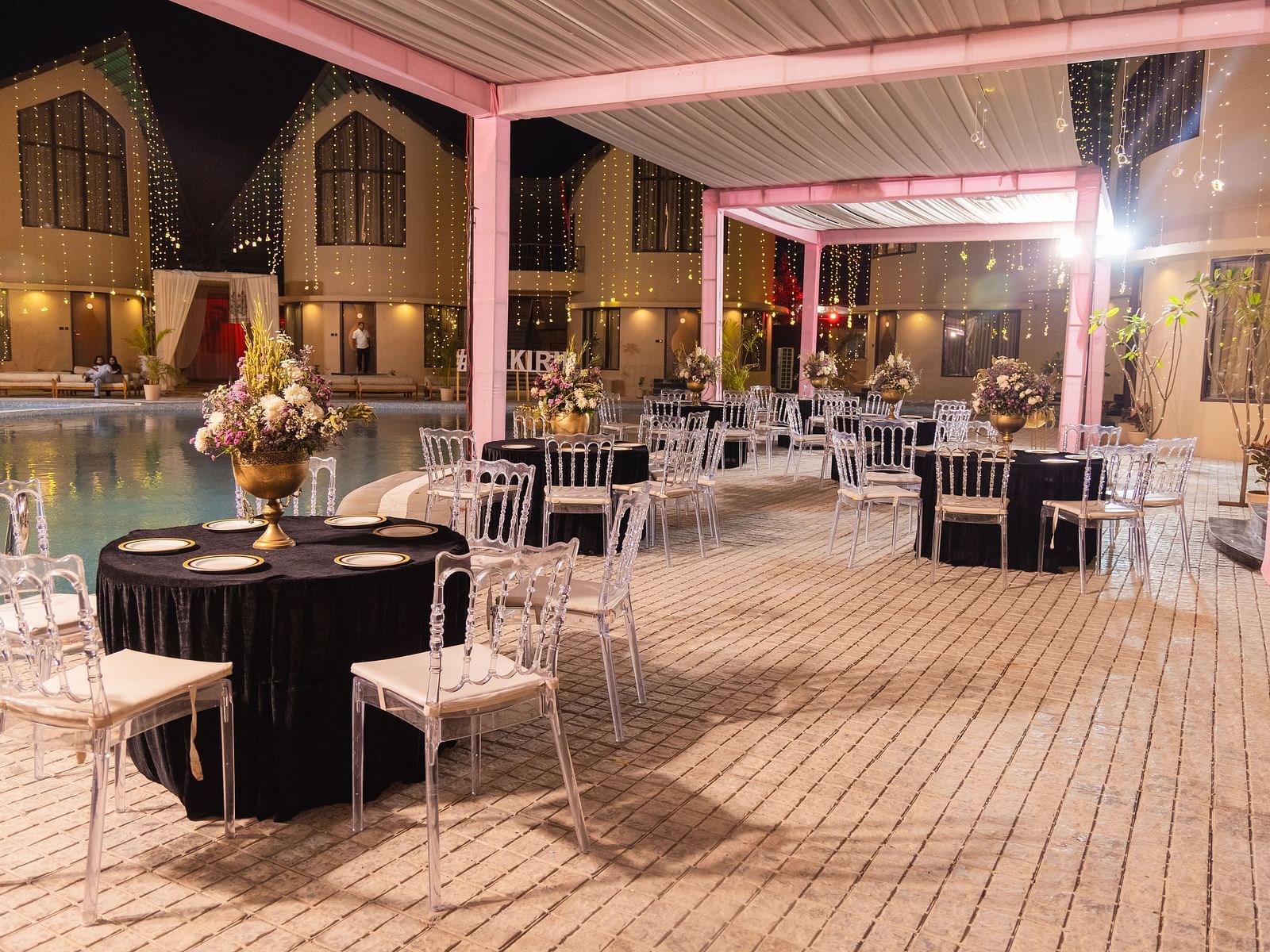 An outdoor event space is prepared with tables and chairs under a white canopy at dusk | The Qualia Resort Club & Brewery, Udaipur