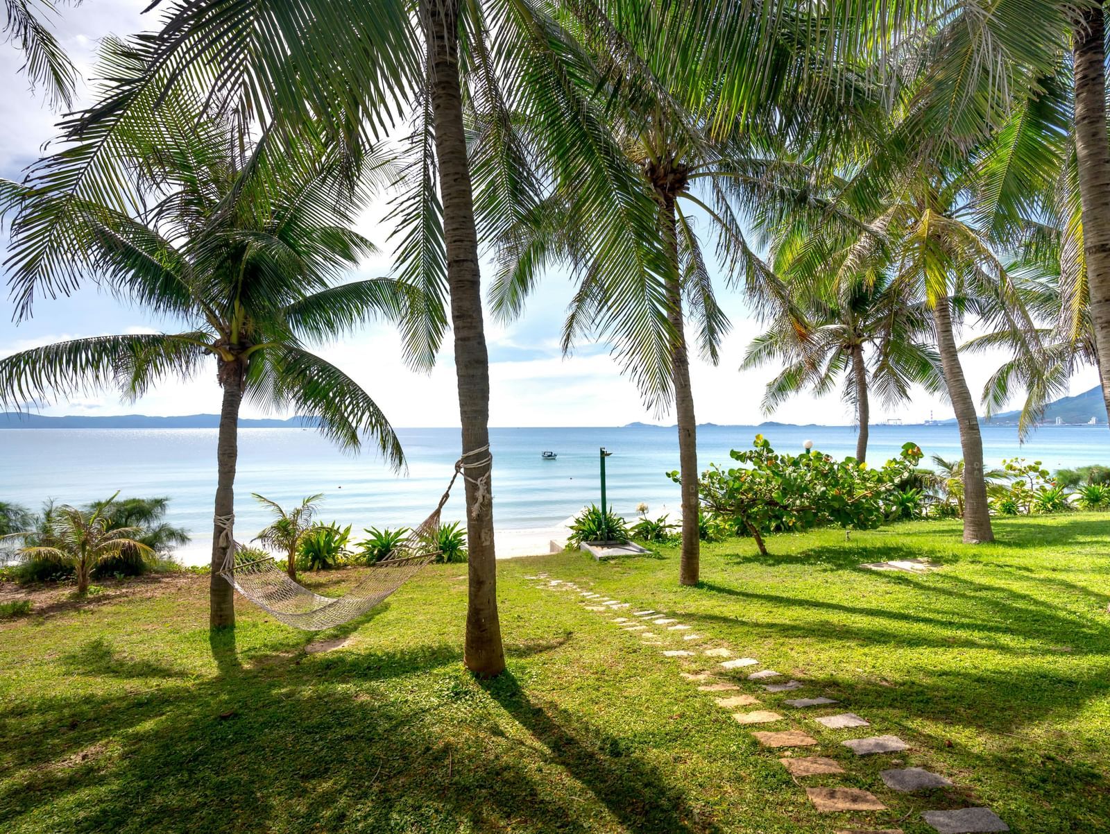 Walking path along the green trees with the ocean visible at the backdrop.