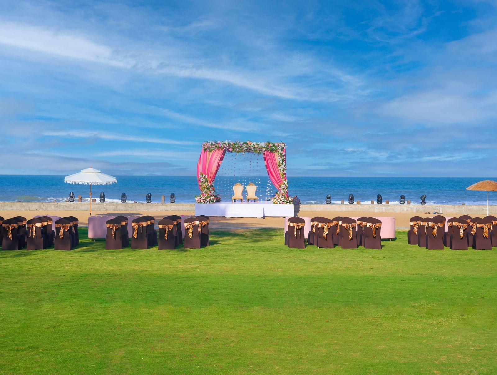 Outdoor lawn with  decorated chairs  and stage with two chairs featuring the sea and the sky at the backdrop at Grande bay Resort & Spa.