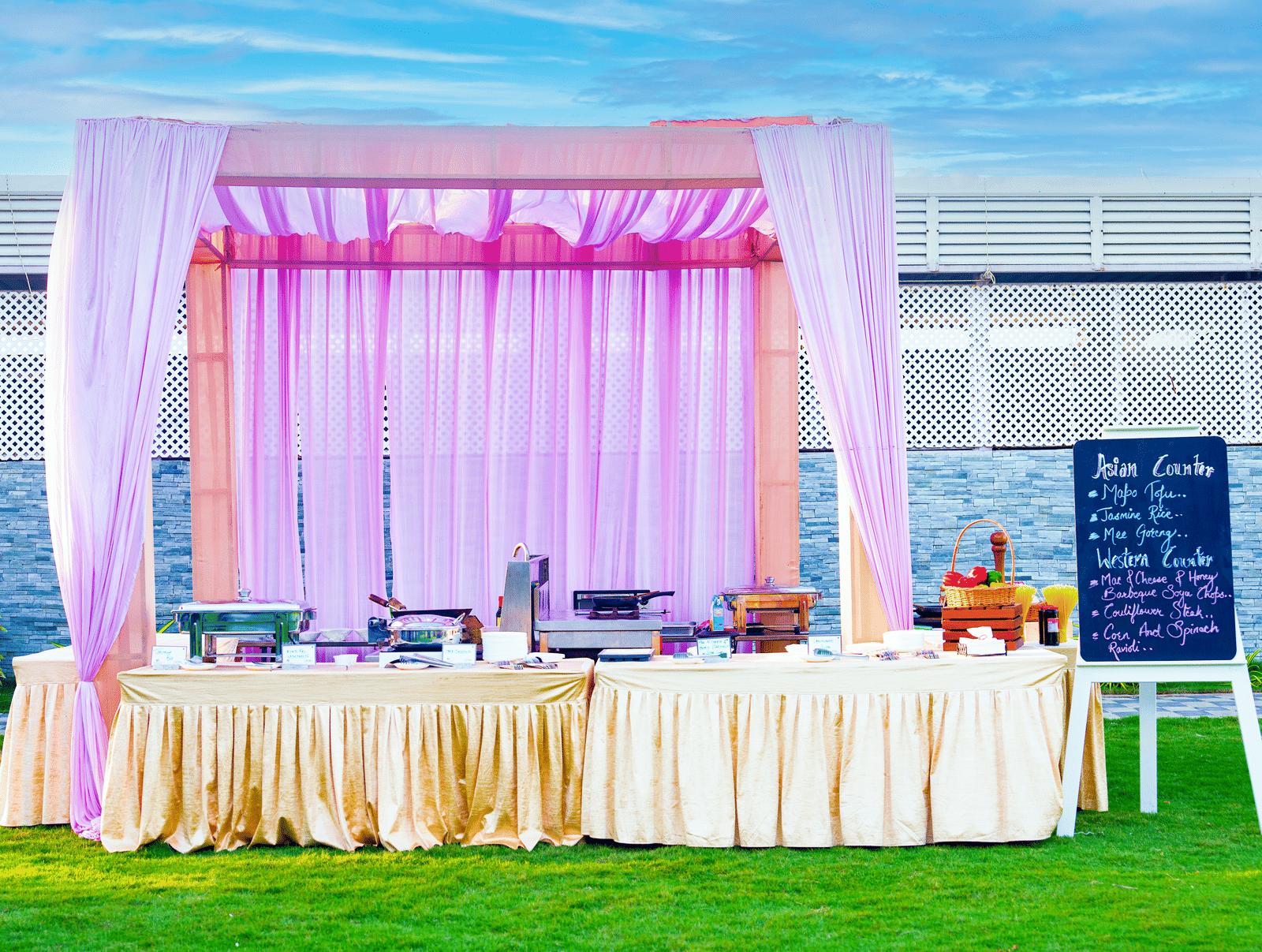 Outdoor buffet counter decorated with lavender drapes set on a green lawn - Grande Bay Resort & Spa, Mamallapuram