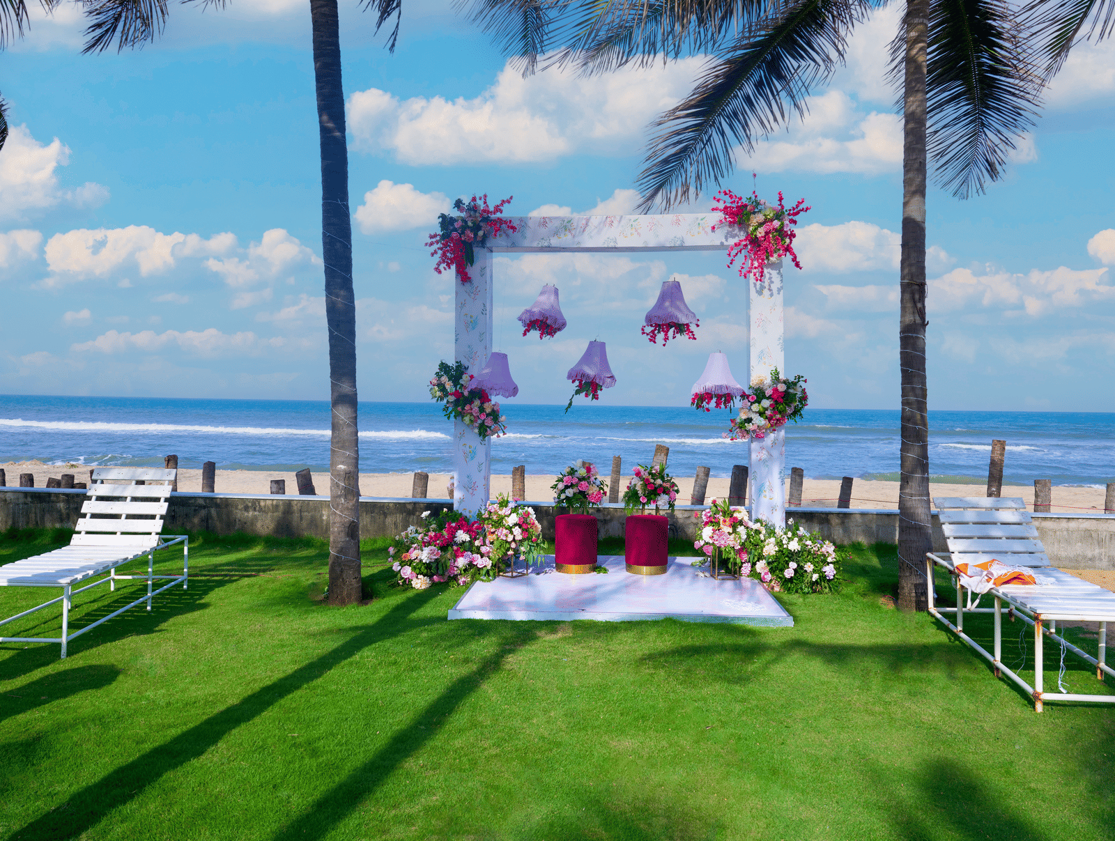 Outdoor garden seating arrangement with floral backdrop overlooking the sea - Grande Bay Resort & Spa, Mamallapuram