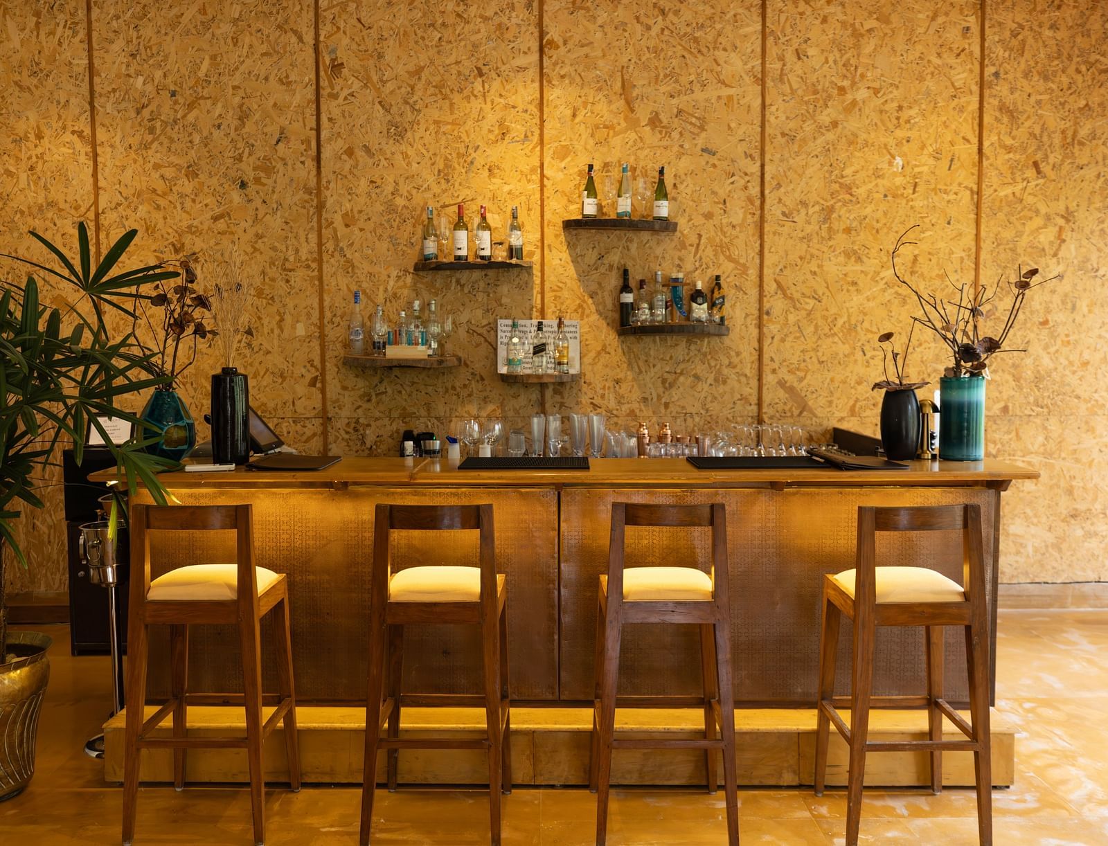 The bar counter at Saraca Bar at Saraca Resort & Spa Corbett with a warm ambience and indoor plants placed besides it