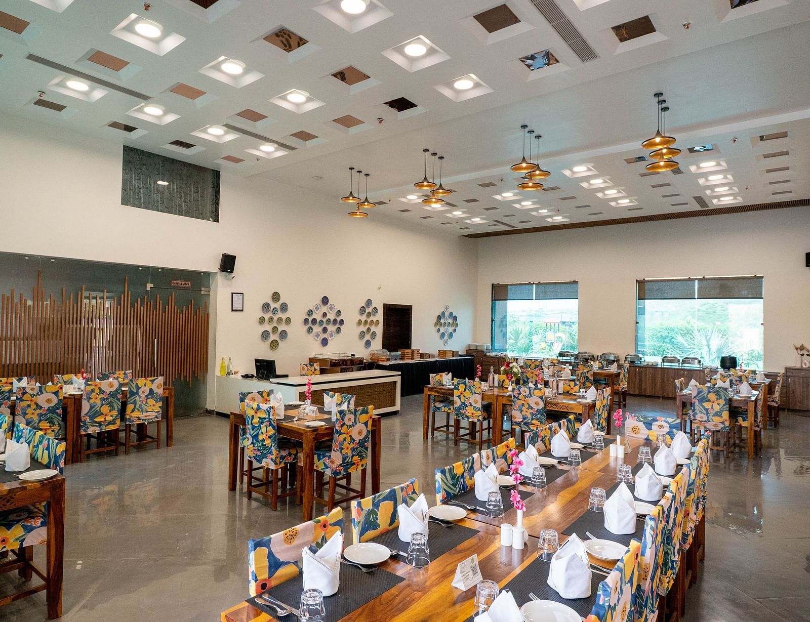 Wide-angle view of Bay Leaf Restaurant offering a buffet setup and spacious seating arrangements and a help desk at the Bamboo Saa Mulberry Resort, Pushkar.