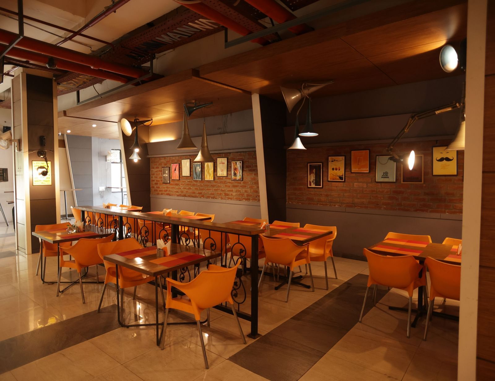 corner view image of a dimly lit dining area with chairs and tables arranged with chic interiors - Max Hotel, Jabalpur