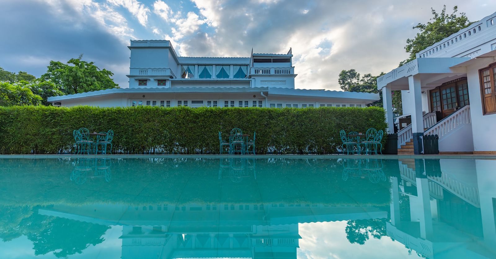 Outdoor swimming pool at Saraca Hotel, Lucknow with the hotel building in the backdrop on a cloudy day