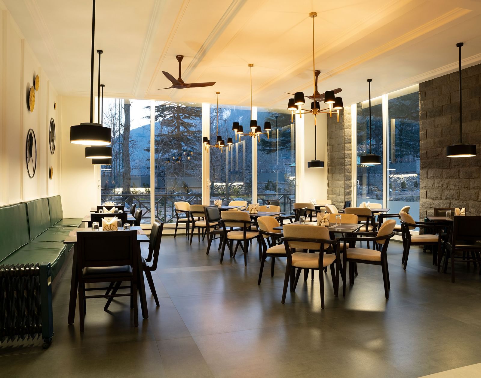 Bright dining area with floor-to-ceiling windows and elegant seating at Nivasana Manali.