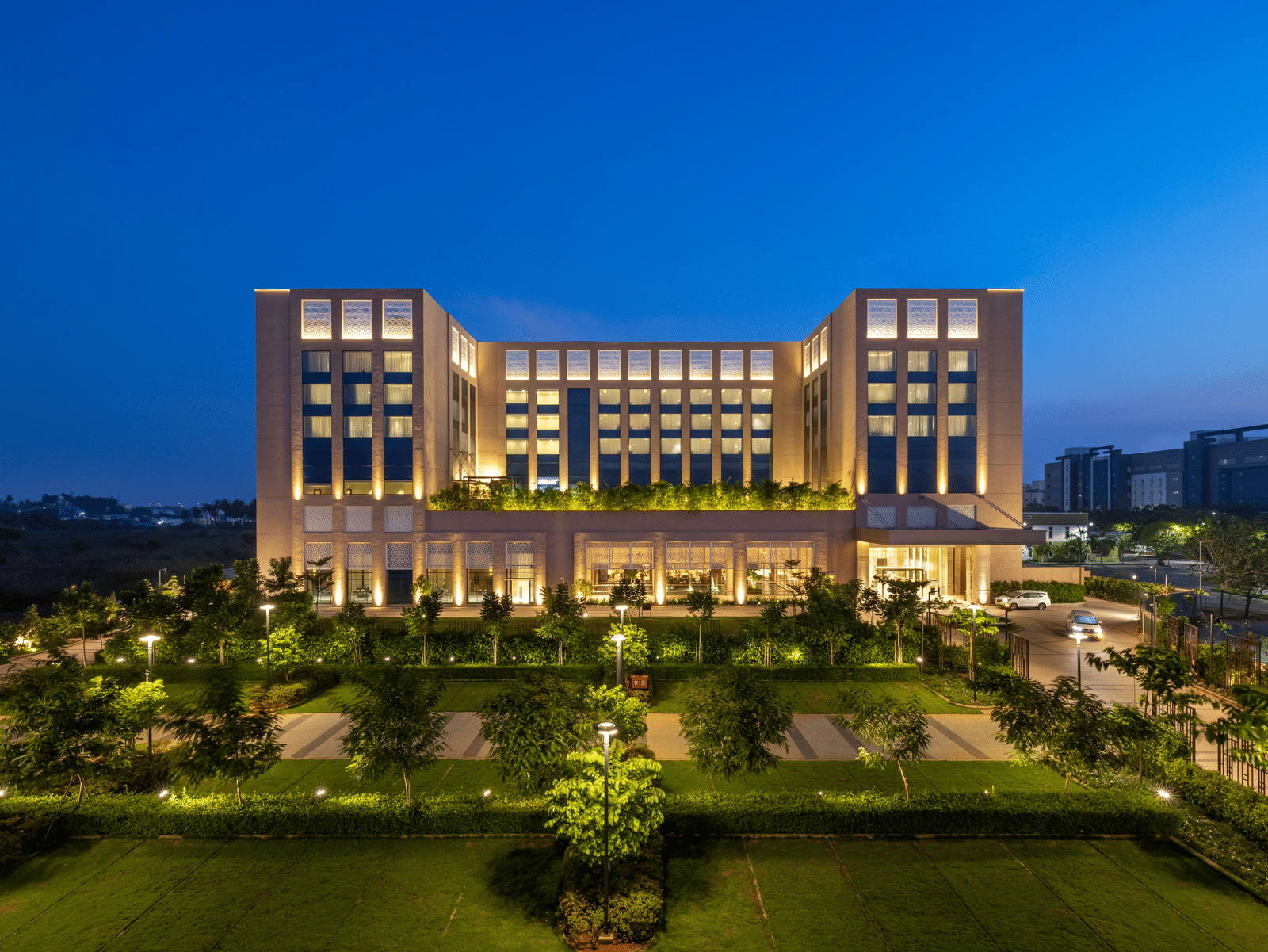 A striking twilight aerial perspective of the hotel, surrounded by manicured lawns - Grand Madurai by GRT Hotels
