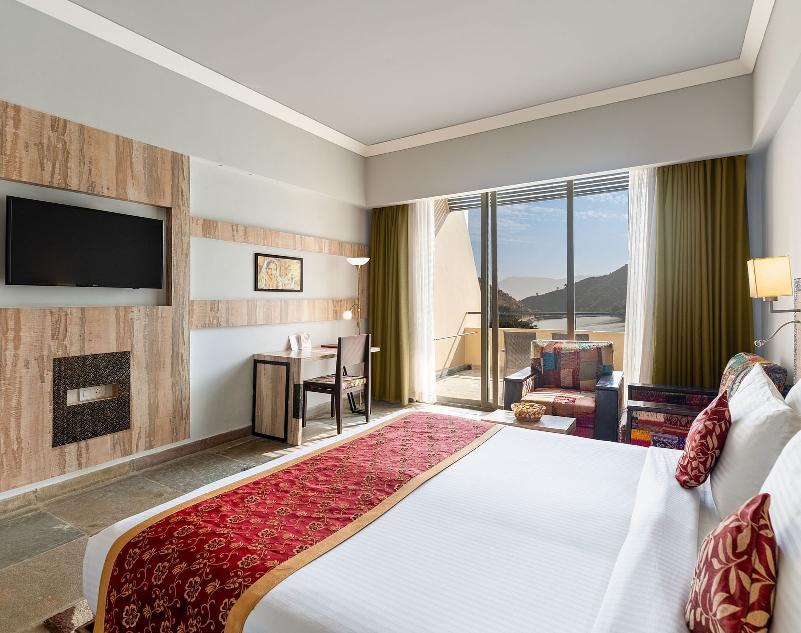 A close-up shot of a bed, opposite to it is a tv mounted on the wall - Via Lakhela Resort & Spa