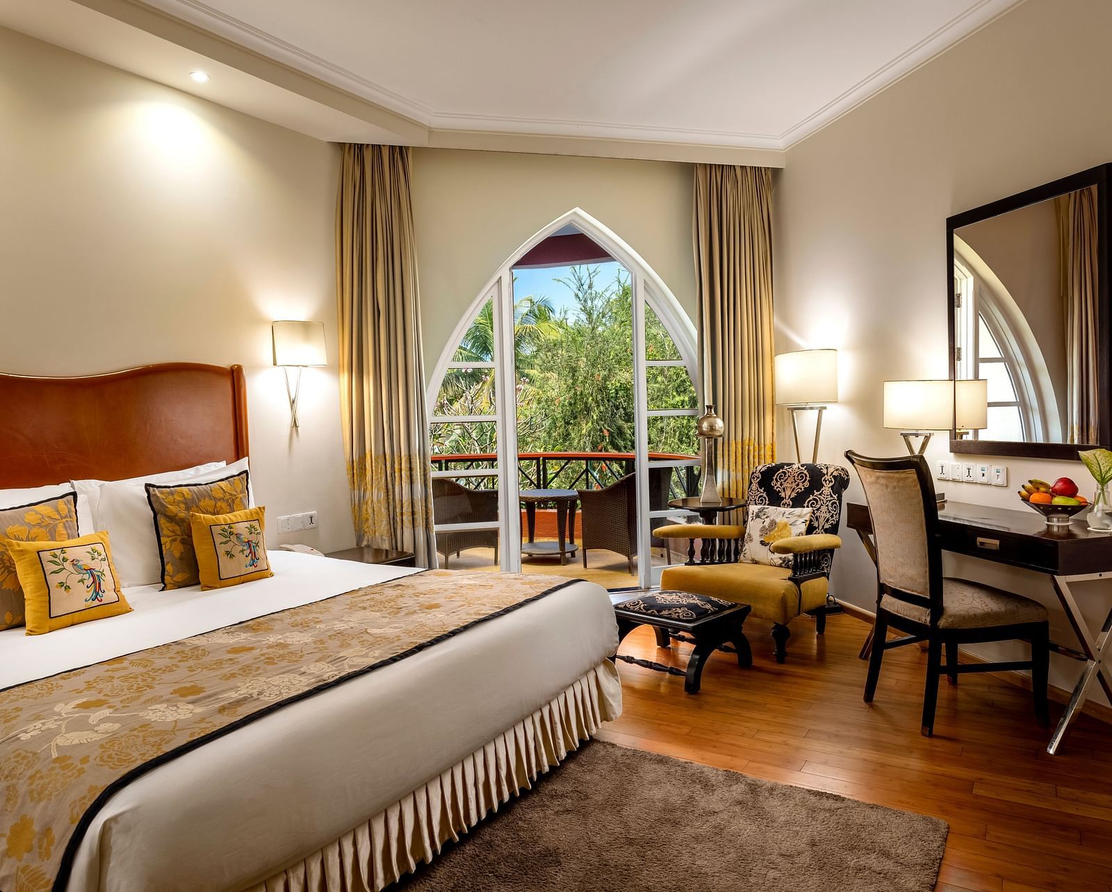 a double bed with side tables, lamps and mirror on the wall inside Deluxe Suite - Caravela Beach Resort Goa.