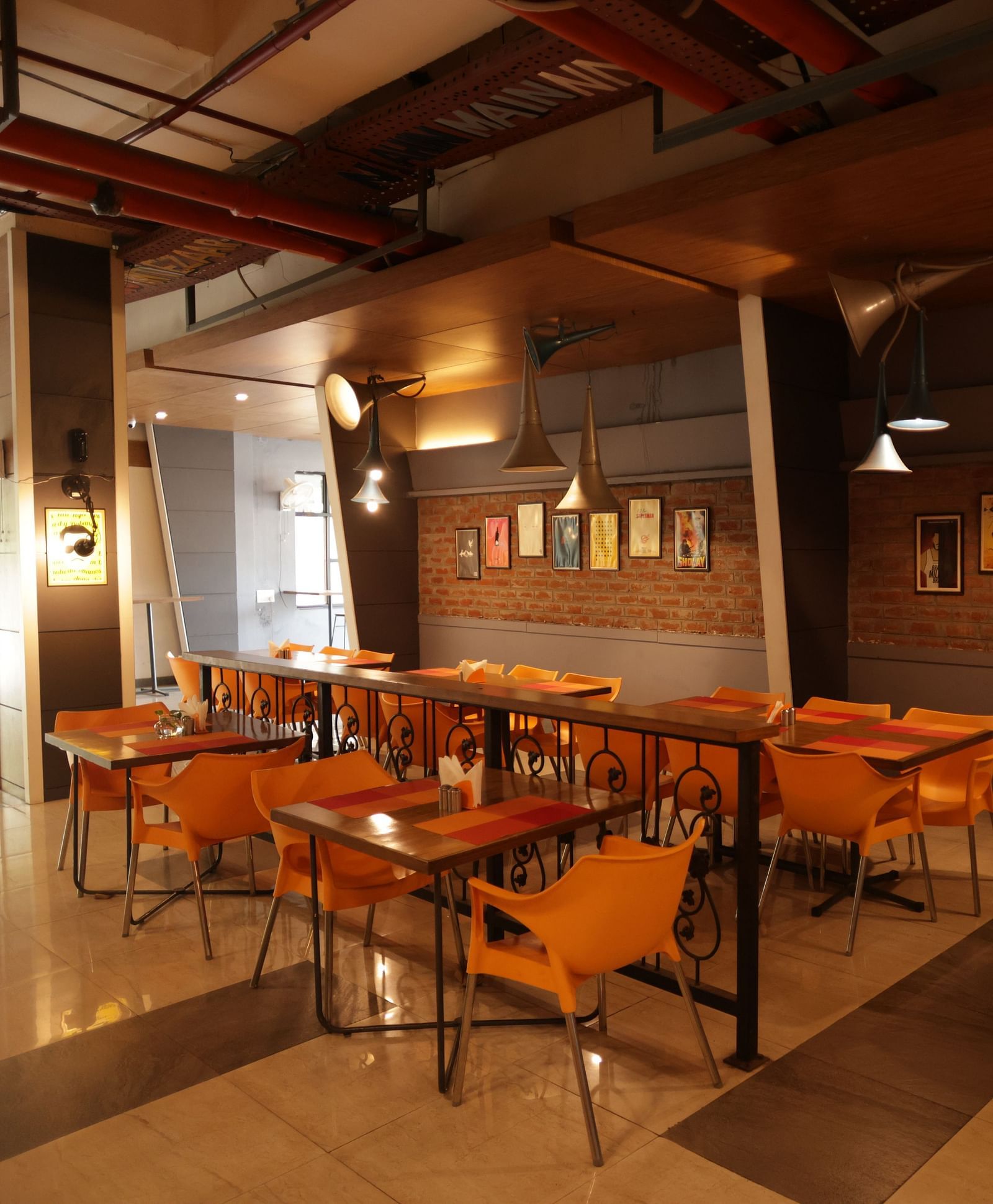 corner view image of a dimly lit dining area with chairs and tables arranged with chic interiors - Max Hotel, Jabalpur