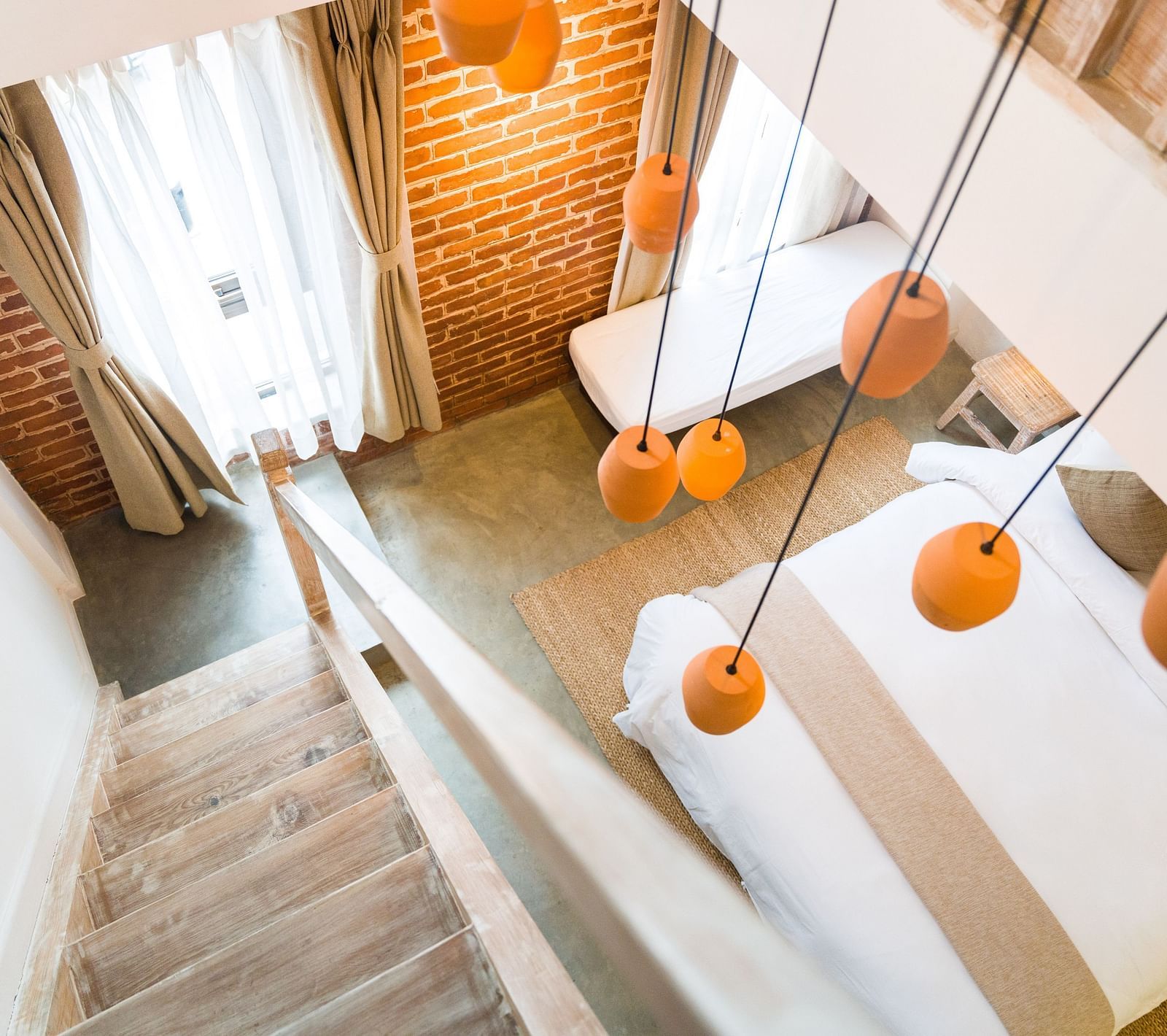 An aerial shot of the deluxe loft room with a staircase and chandelier hanging above it - The Nanee