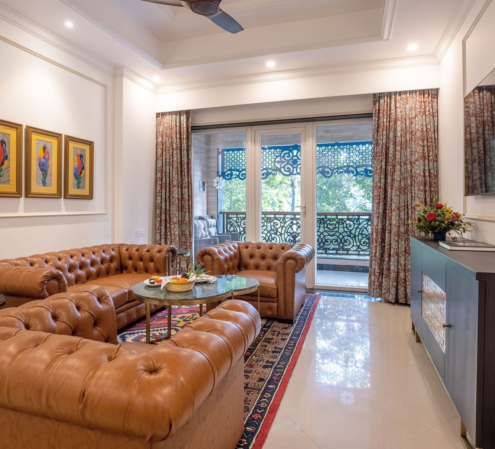 A luxury living area with a sofa set, large glass windows, and a wall-mounted TV at MAYFAIR Palm Beach Resort, Gopalpur-On-Sea