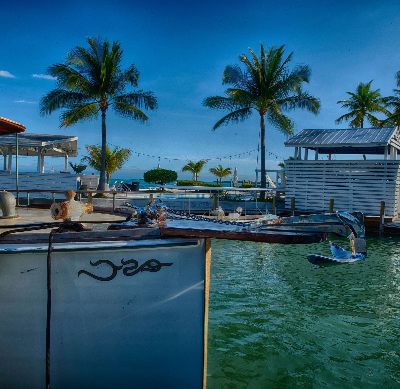 View of Casa Morada's waterfront with a docked boat, palm trees, and resort buildings in the background.