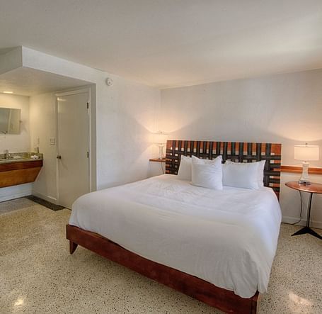 Bedroom at Casa Morada with a king bed, wooden headboard, and a sitting area near large windows.