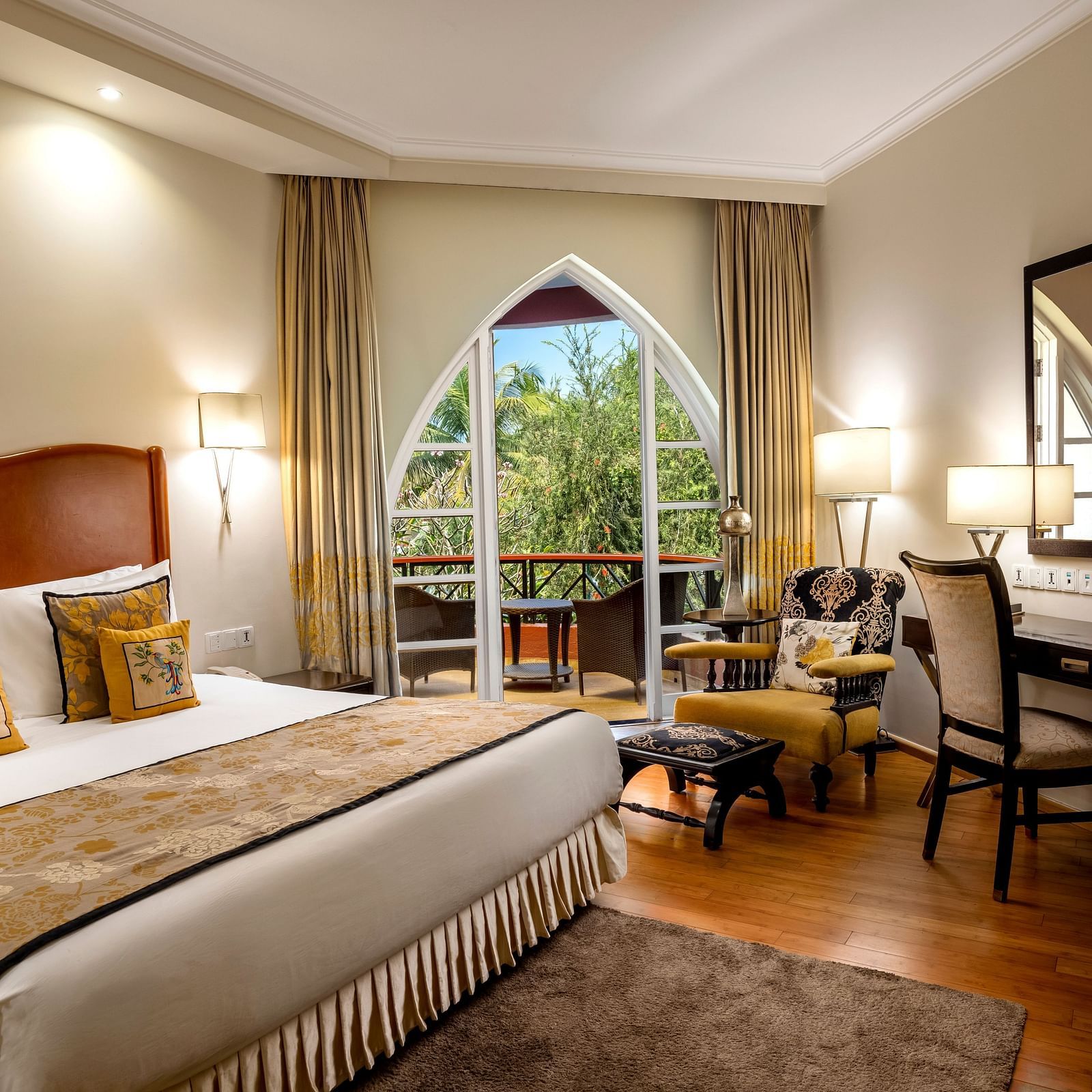 a double bed with side tables, lamps and mirror on the wall inside Deluxe Suite - Caravela Beach Resort Goa.