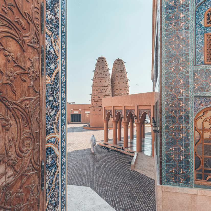 A view of Katara village in Doha with beautiful mosaic walls on the buildings and a person walking.