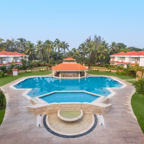 Symmetrical view of a pool with a gazebo and resort villas on either side.