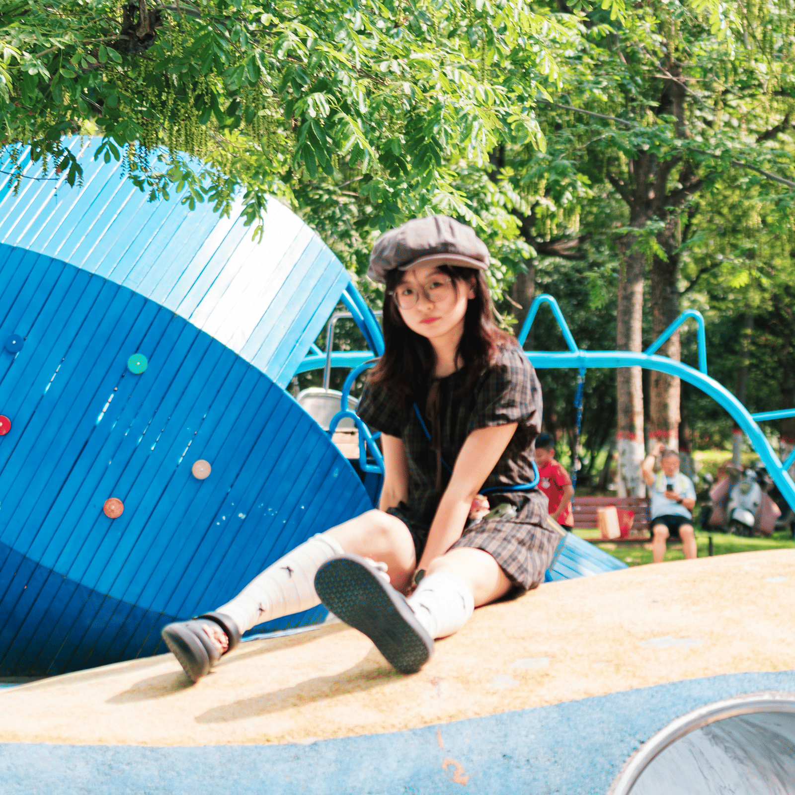 A view of a child posing for a picture while sitting on a slide in an adventure park.