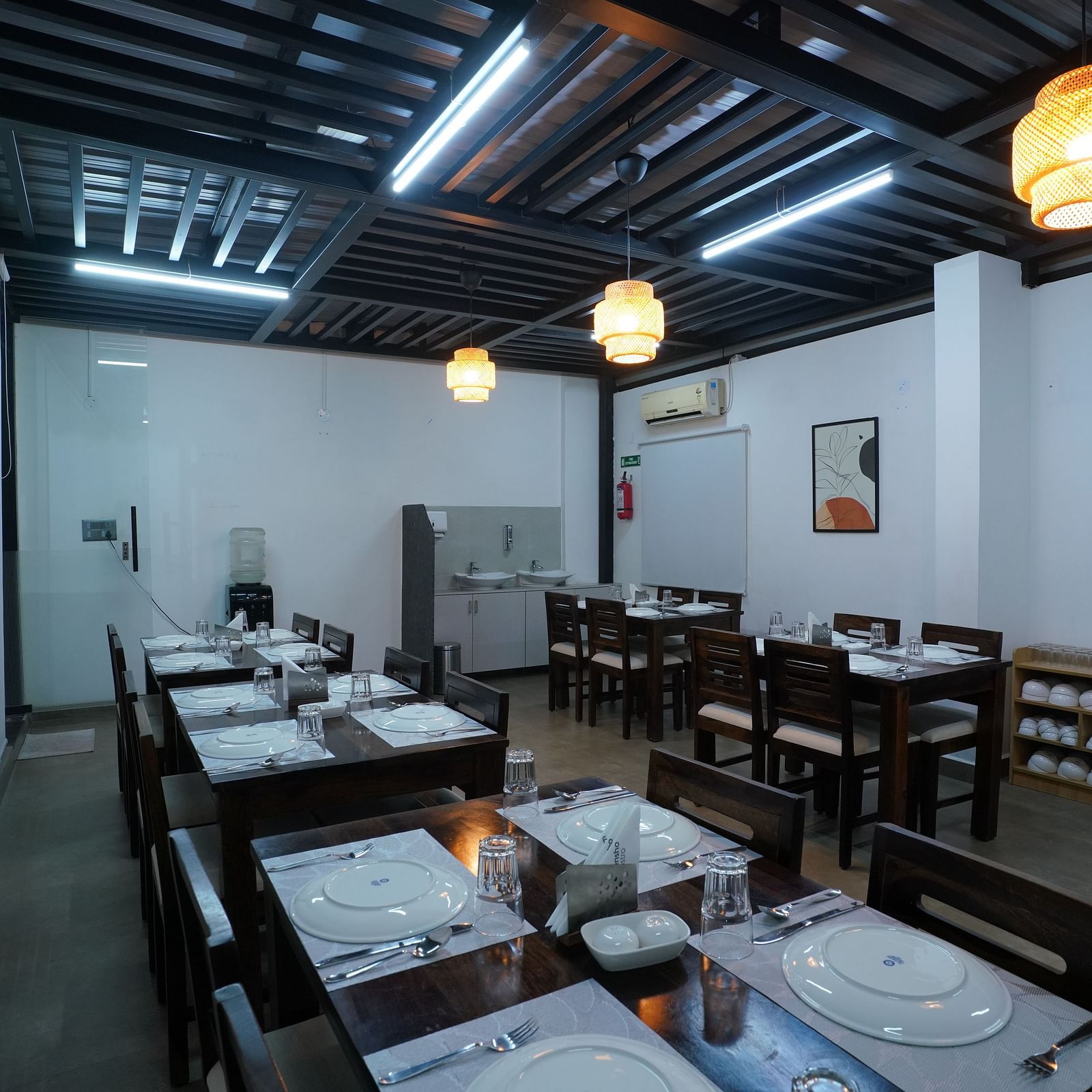 A rooftop dining area with tables and chairs, partially shaded, overlooking a bright outdoor space at Kyzen Smart Stays.