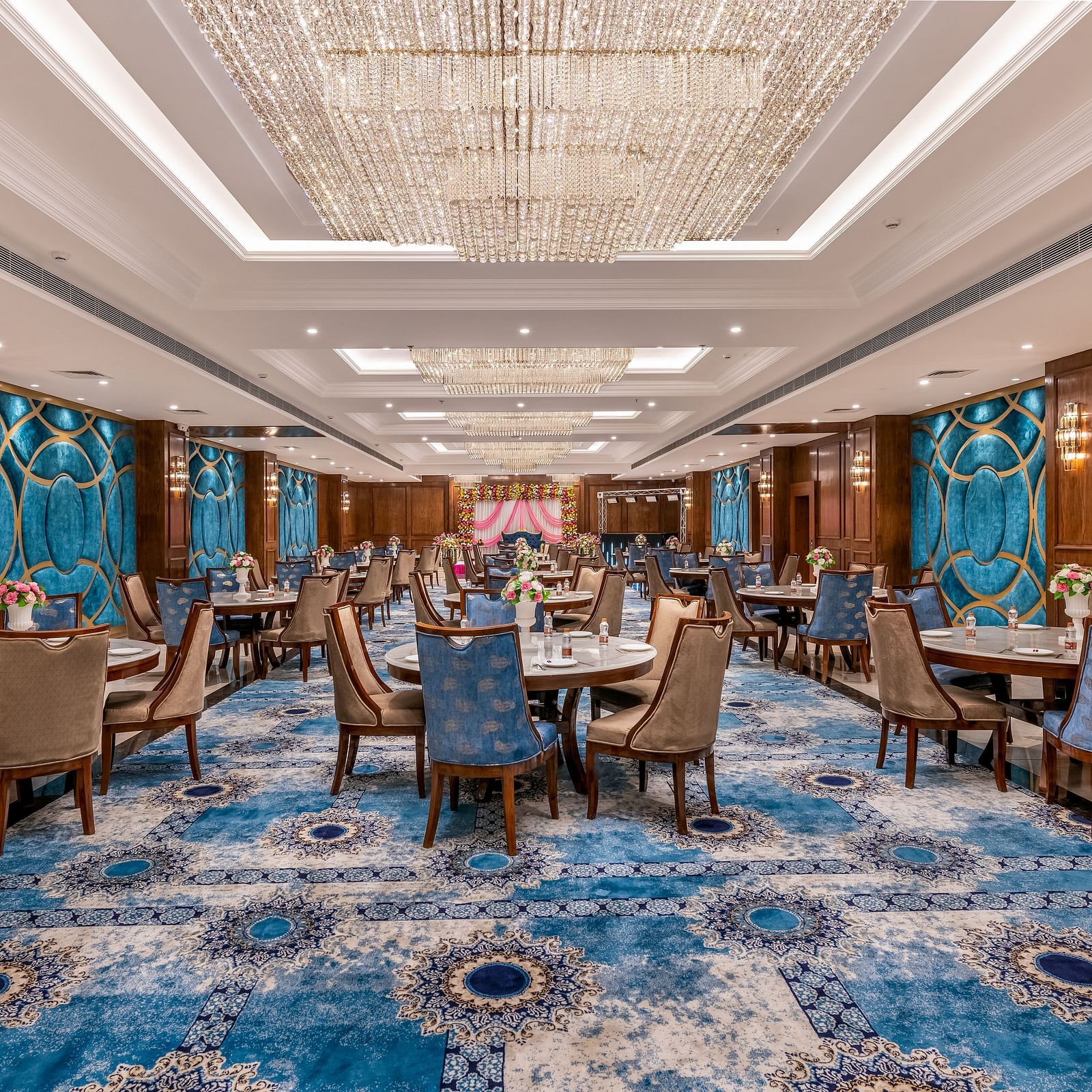 Elegant Banquet with blue-patterned carpet, wooden walls, and chandelier lighting.