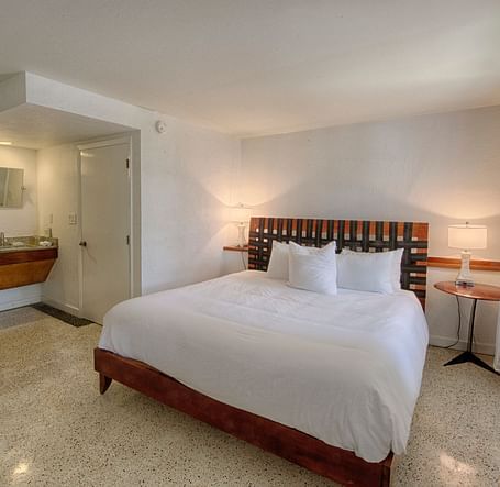 Bedroom at Casa Morada with a king bed, wooden headboard, and a sitting area near large windows.
