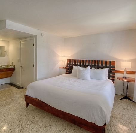 Bedroom at Casa Morada with a king bed, wooden headboard, and a sitting area near large windows.