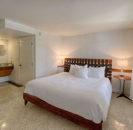 Bedroom at Casa Morada with a king bed, wooden headboard, and a sitting area near large windows.