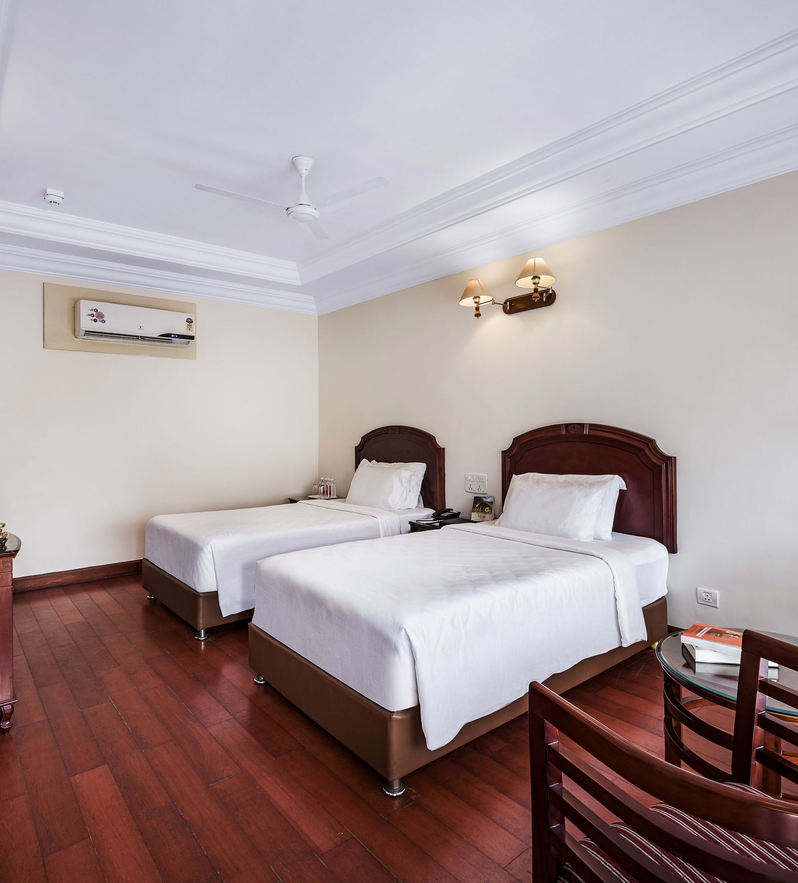 An image of the River View Room With Verandah featuring two single beds, bed side table, lamps, flat screen TV, and chairs - GReaT Trails River View Resort Thanjavur By GRT Hotels