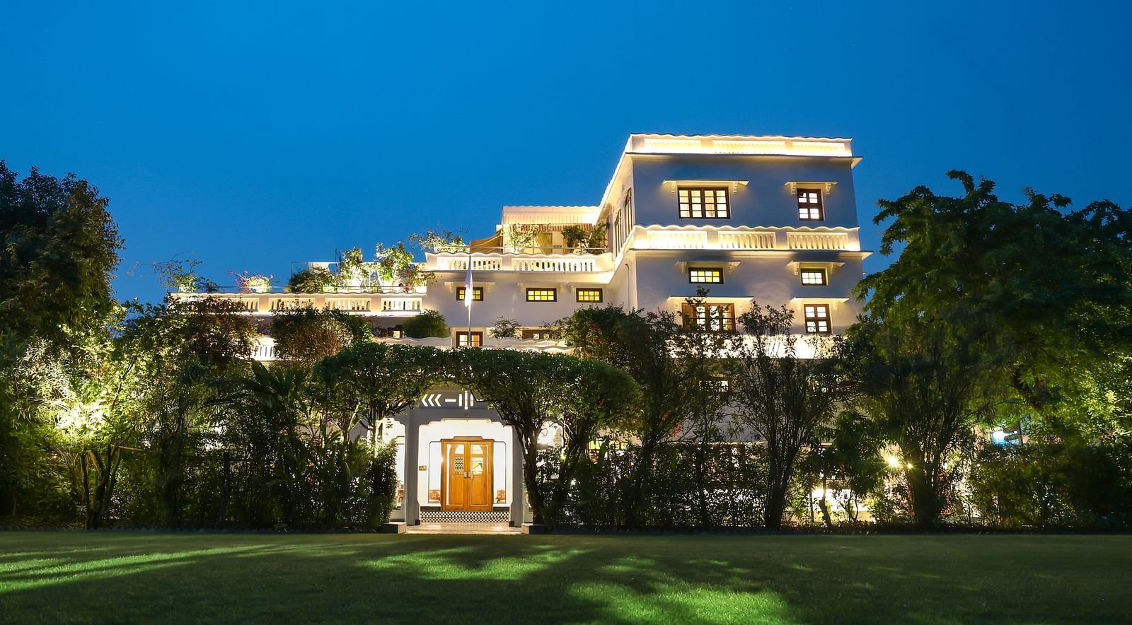 A wide view of the garden area of Saraca Hotel, Lucknow with the hotel building in the background during blue hour