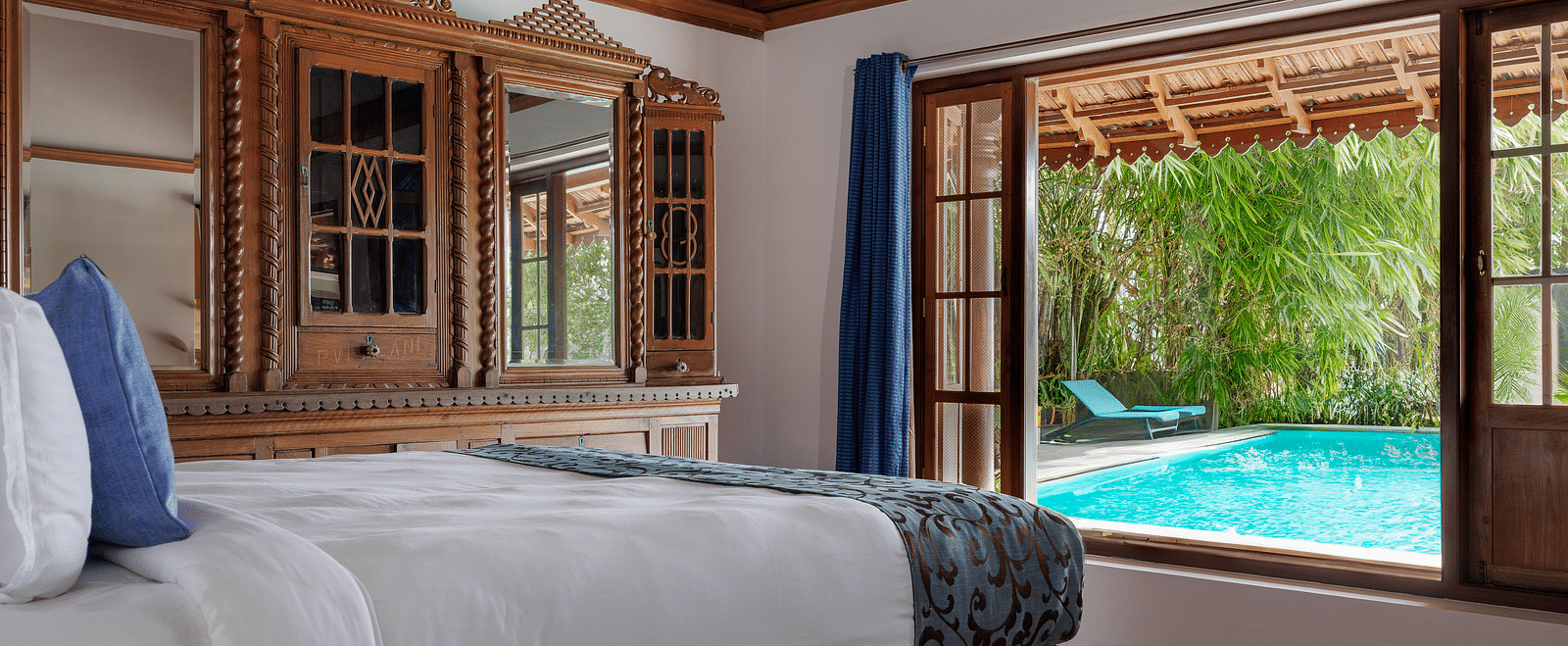 A shot of a room taken from an angle showcasing the bed facing a huge window with the view of the pool outside - BluSalzz Villas - Muhamma Resort, Alleppey