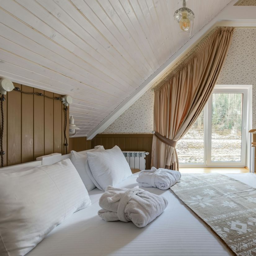 An attic-style room featuring twin beds with white linens on them and a wall-mounted TV.