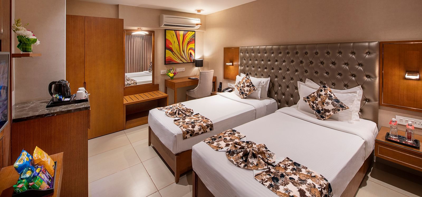 A hotel room with twin beds and wooden furniture - SK Lords Inn Ahmedabad